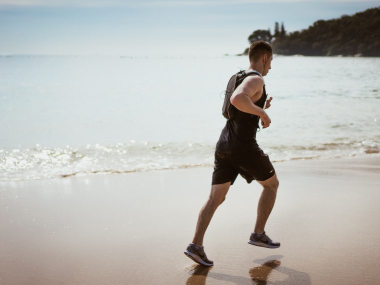 Man Wearing Black Tank Top and Running on Seashore