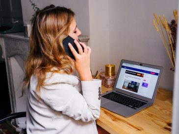 a woman sitting at a desk with a laptop and a phone