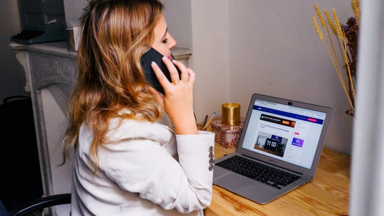 a woman sitting at a desk with a laptop and a phone