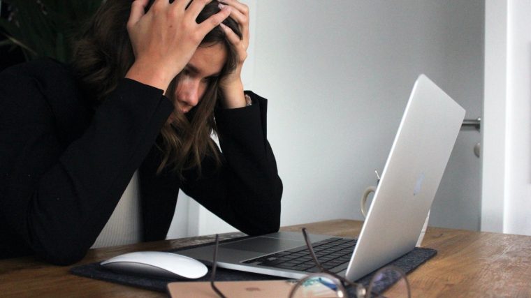 woman in black long sleeve shirt covering her face with her hands