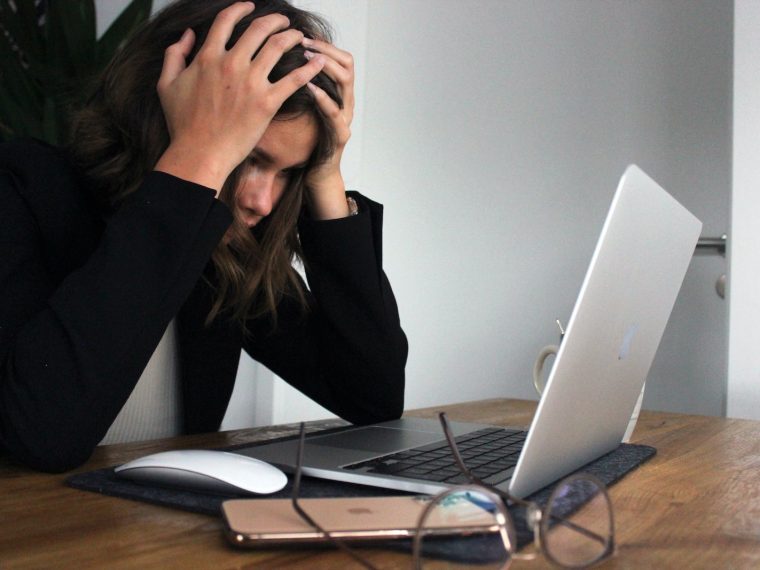 woman in black long sleeve shirt covering her face with her hands