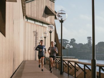 man in black t-shirt and blue shorts running on brown wooden dock during daytime