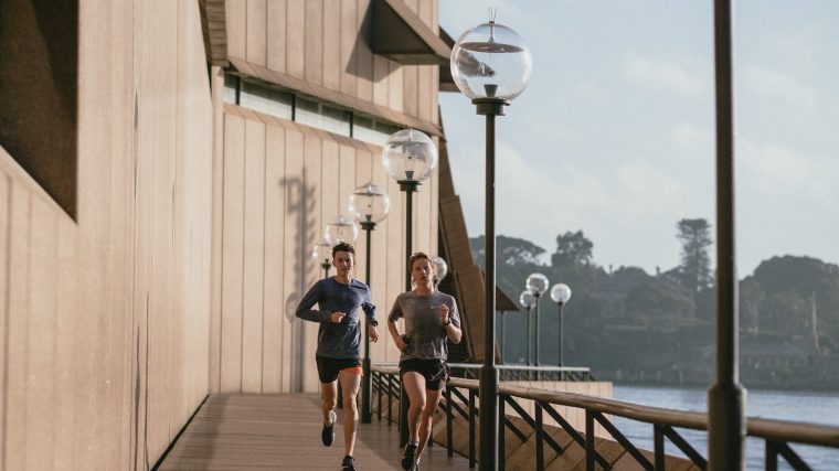 man in black t-shirt and blue shorts running on brown wooden dock during daytime